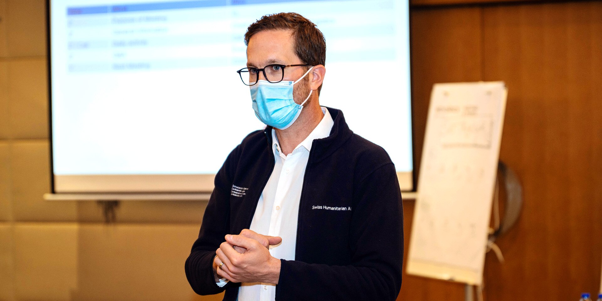 Claude Wandeler stands in front of a screen during a team meeting.