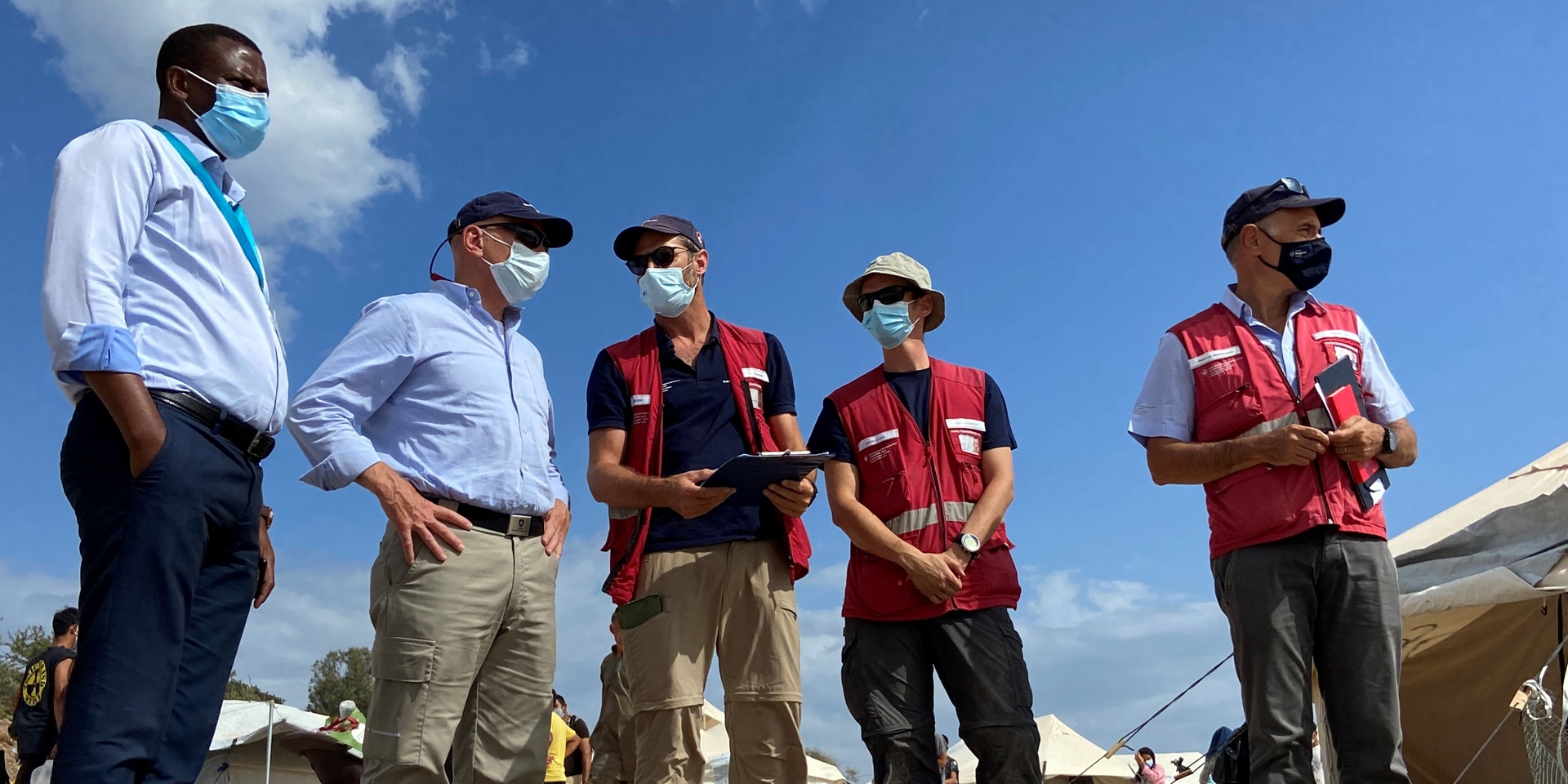 Der Chef der Humanitären Hilfe des Bundes, Manuel Bessler, unterhält sich bei einem Besuch vor Ort mit Experten des Schweizerischen Korps für humanitäre Hilfe und dem stellvertretenden Lagerleiter von Lesbos, Spiros Habimama.