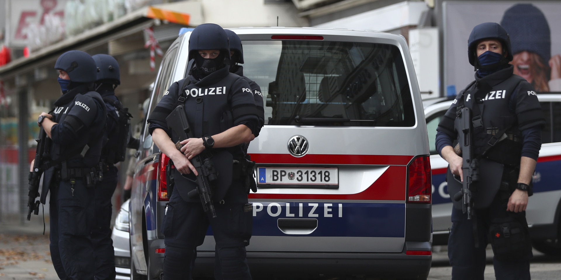 Mehrere schwer bewaffnete österreichische Polizisten stehen vor einem Polizeiauto.