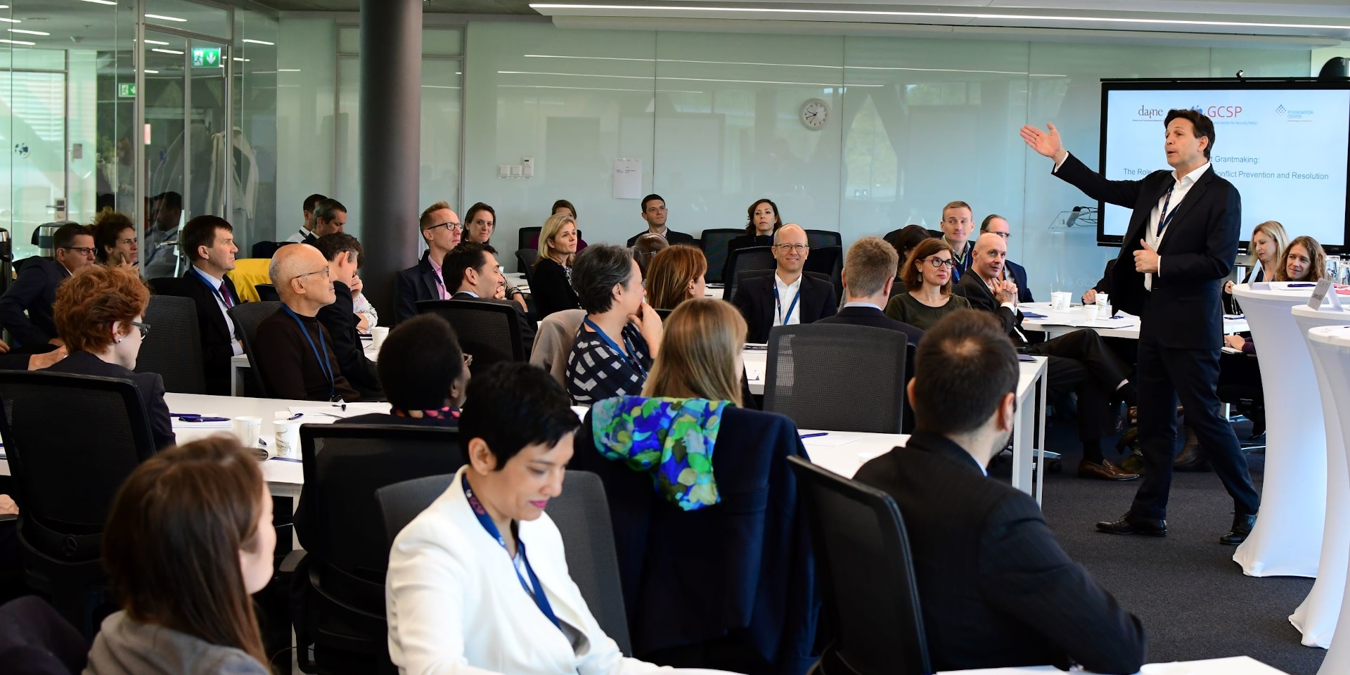 A group of about 25 adults listen intently to the lecture in a classroom. Christian Dussey, Director GCSP is on the right side of the picture. 