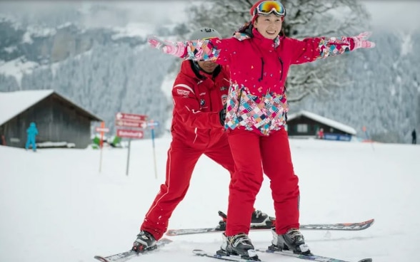 Turista cinese sugli sci con il suo maestro.
