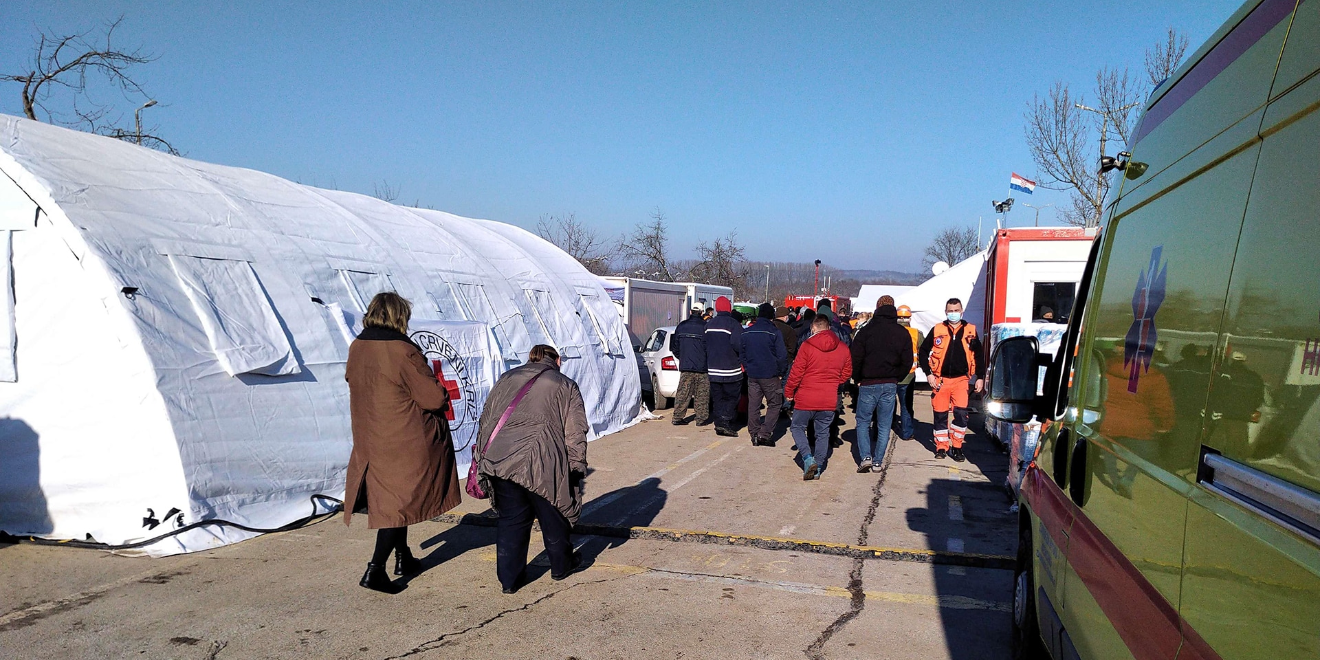 Une tente blanche, une ambulance et d'autres véhicules de la protection civile et des organisations humanitaires. Des gens y travaillent pour apporter de l'aide.