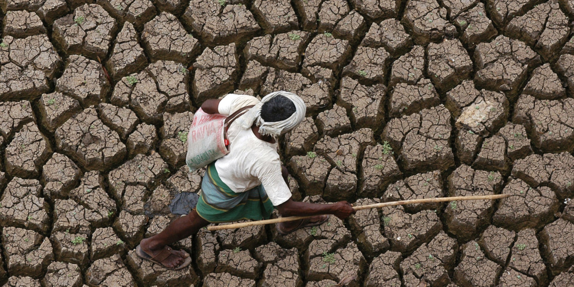 A man walking across a parched field.