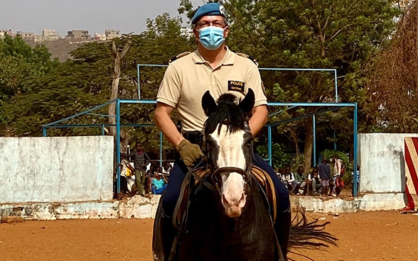 Carl Emery, pieds à l’étrier, sur son cheval brun. 