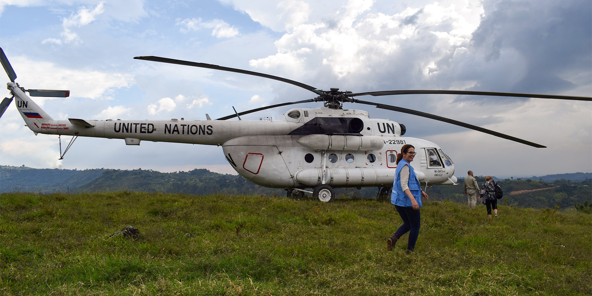 Natalie Kohli in front of a UN helicopter standing on a green lawn.