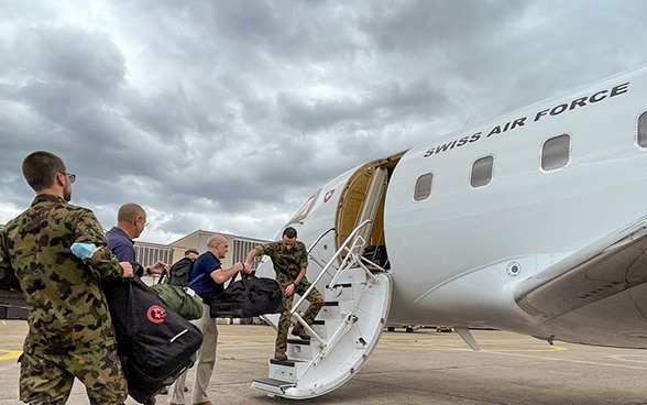  Various people are loading luggage onto a plane.