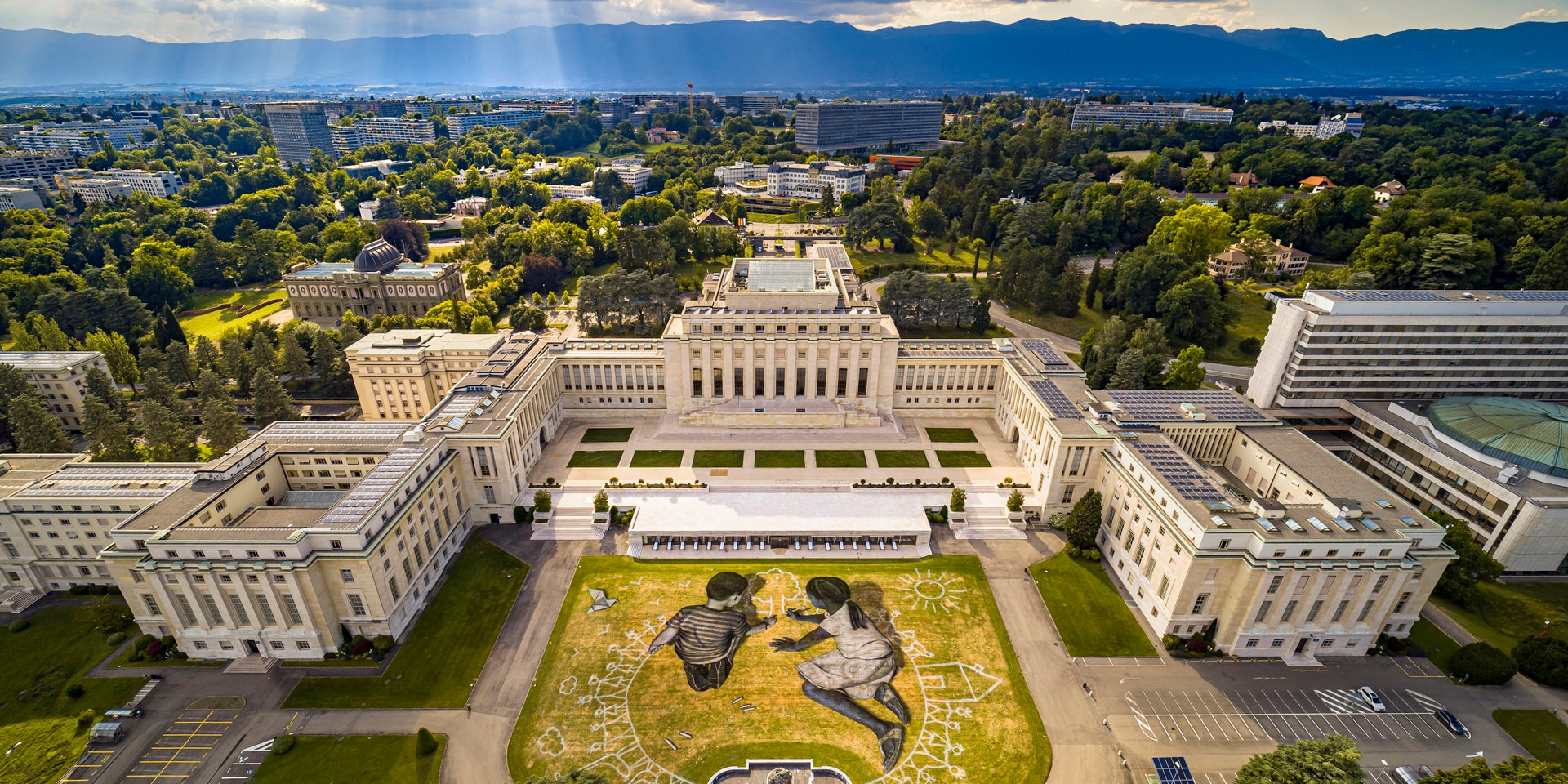 Fresque représentant deux enfants en train de dessiner, réalisée sur la pelouse du parc du Palais des Nations, à Genève.