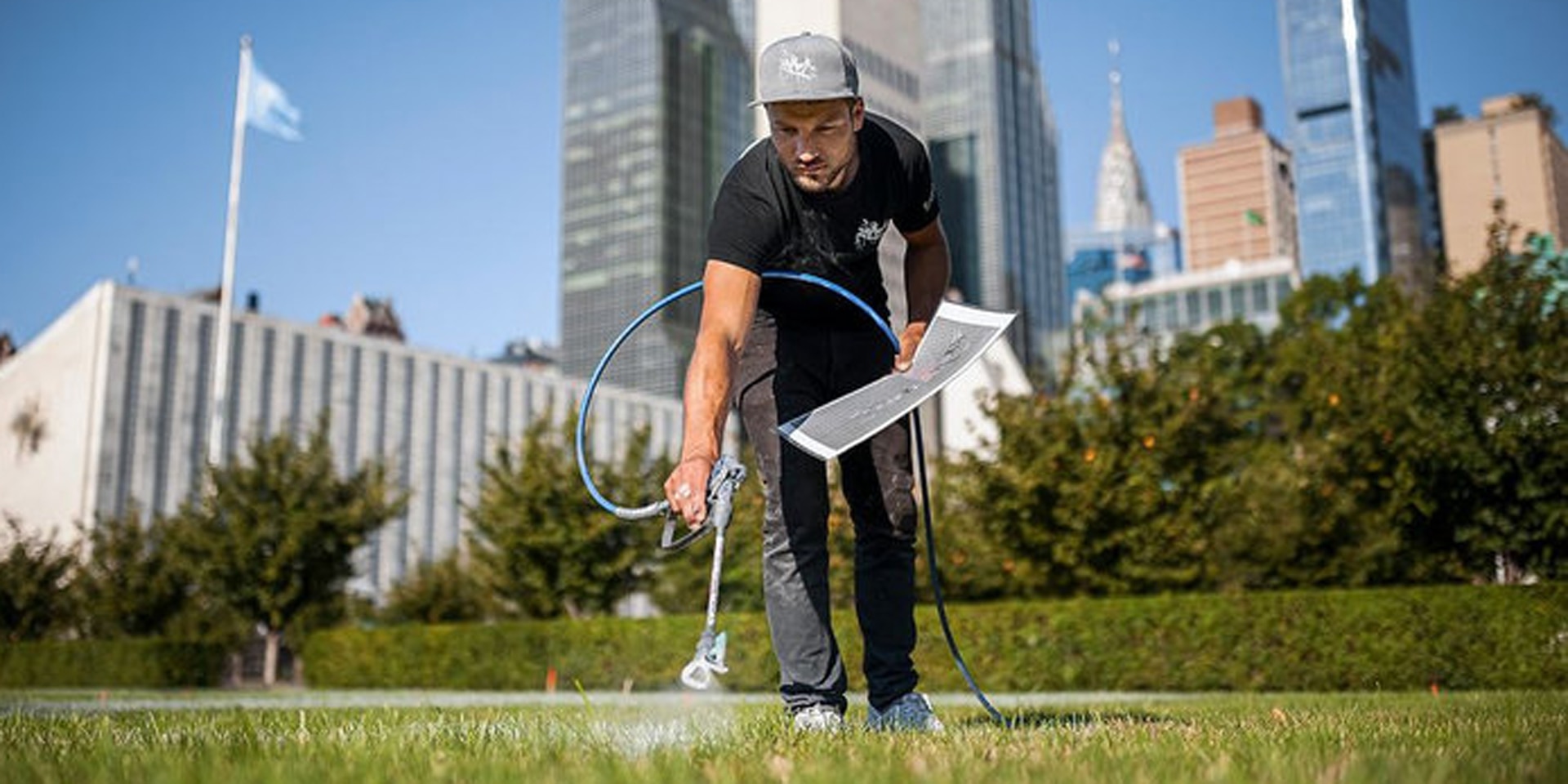 A young man is painting on the lawn in the middle of New York.
