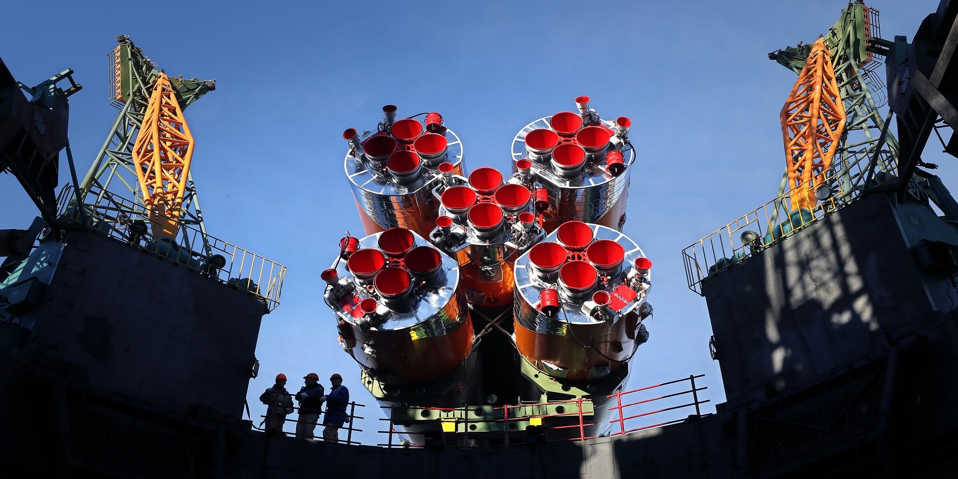 Das Triebwerk einer Rakete neben einer Abschussrampe bei stahlblauem Himmel.