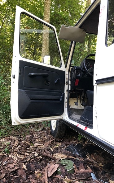 Une mine verte se trouve au sol sous la portière ouverte de la jeep blanche..