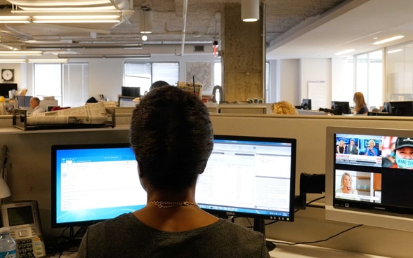 A female journalist sits at her desk in an empty newsroom.