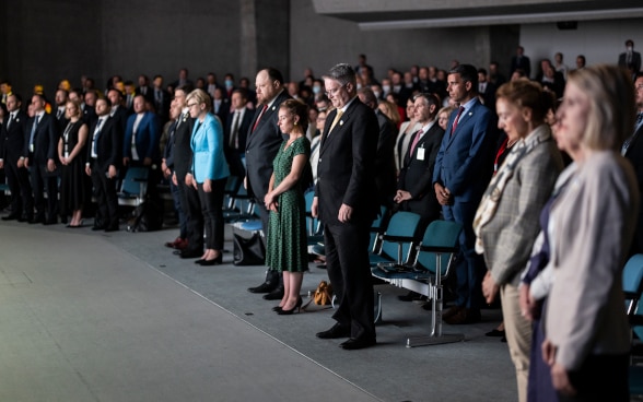 Dans la grande salle du Palazzo dei Congressi, les participants à la séance plénière de clôture observent une minute de silence.