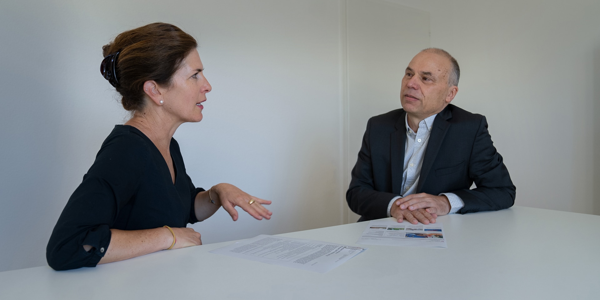 Debora Kern et Daniel Birchmeier, assis à la même table, consultent des documents et sont engagés dans une discussion animée. 