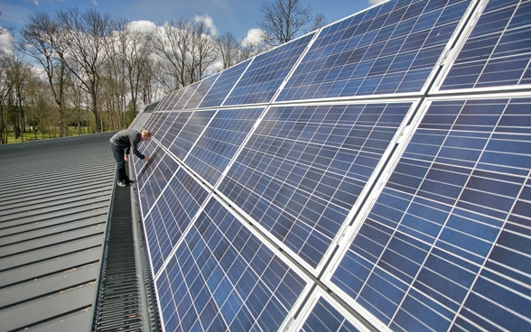 Ein Mann arbeitet an einer Solarzellenkonstruktion. 