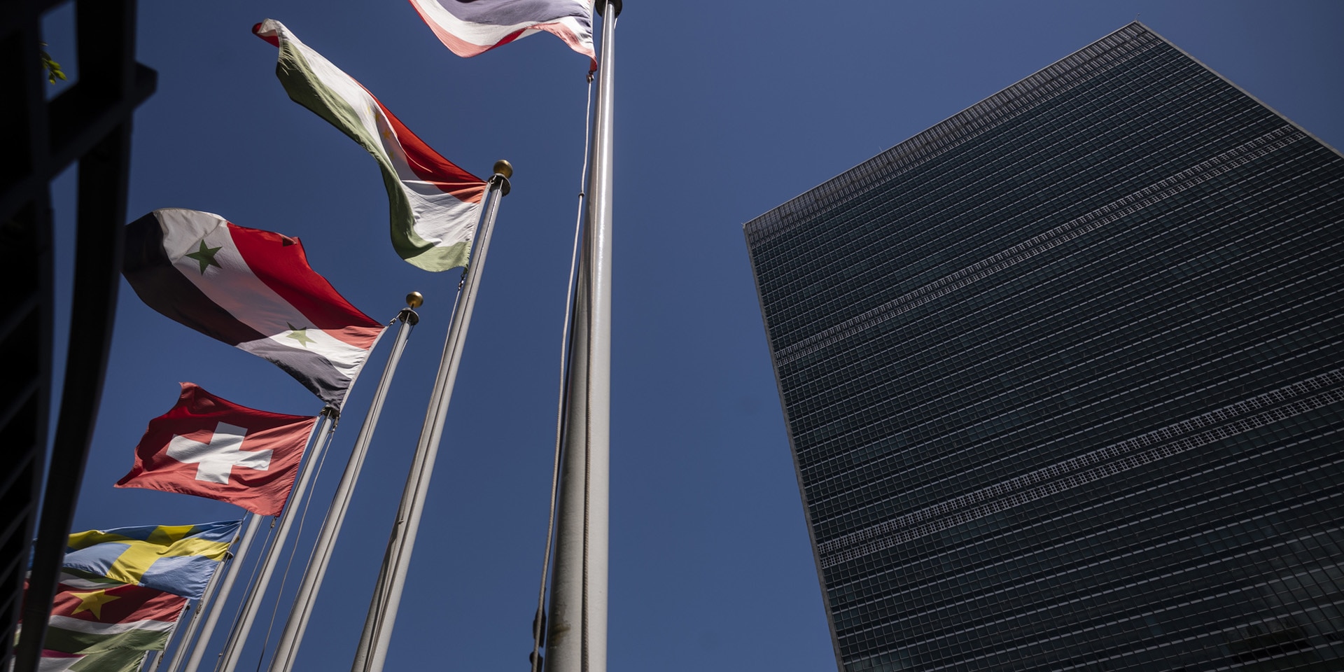 Le drapeau suisse flotte devant le bâtiment de l’ONU à New York, à côté des drapeaux des autres États membres.