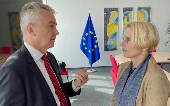 Livia Leu und Juraj Nociar diskutieren mit der Europaflagge im Hintergrund.