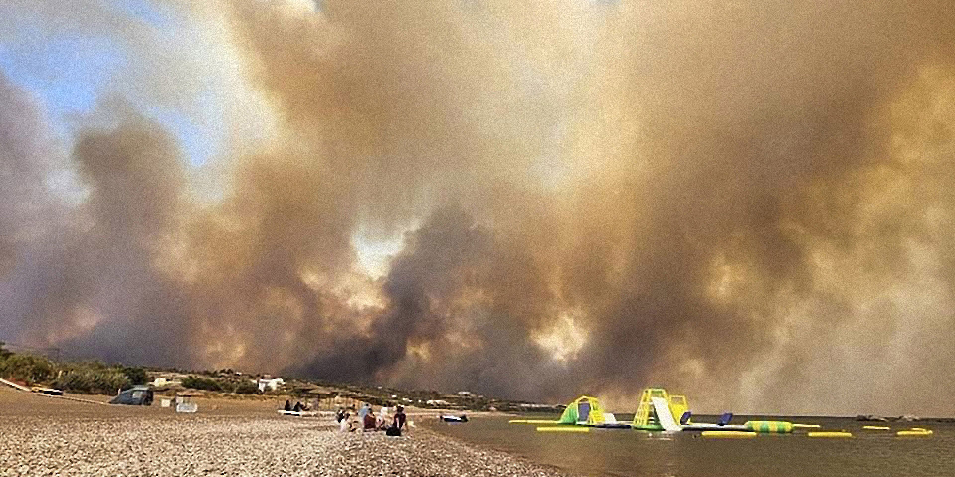 Una spiaggia con spesse nuvole di fumo in cielo.