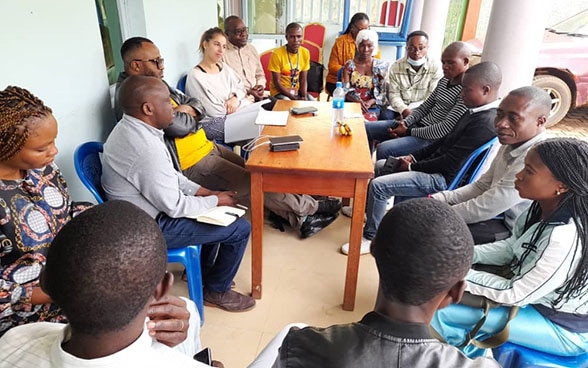  A group of people in Congo talks sitting around a table.