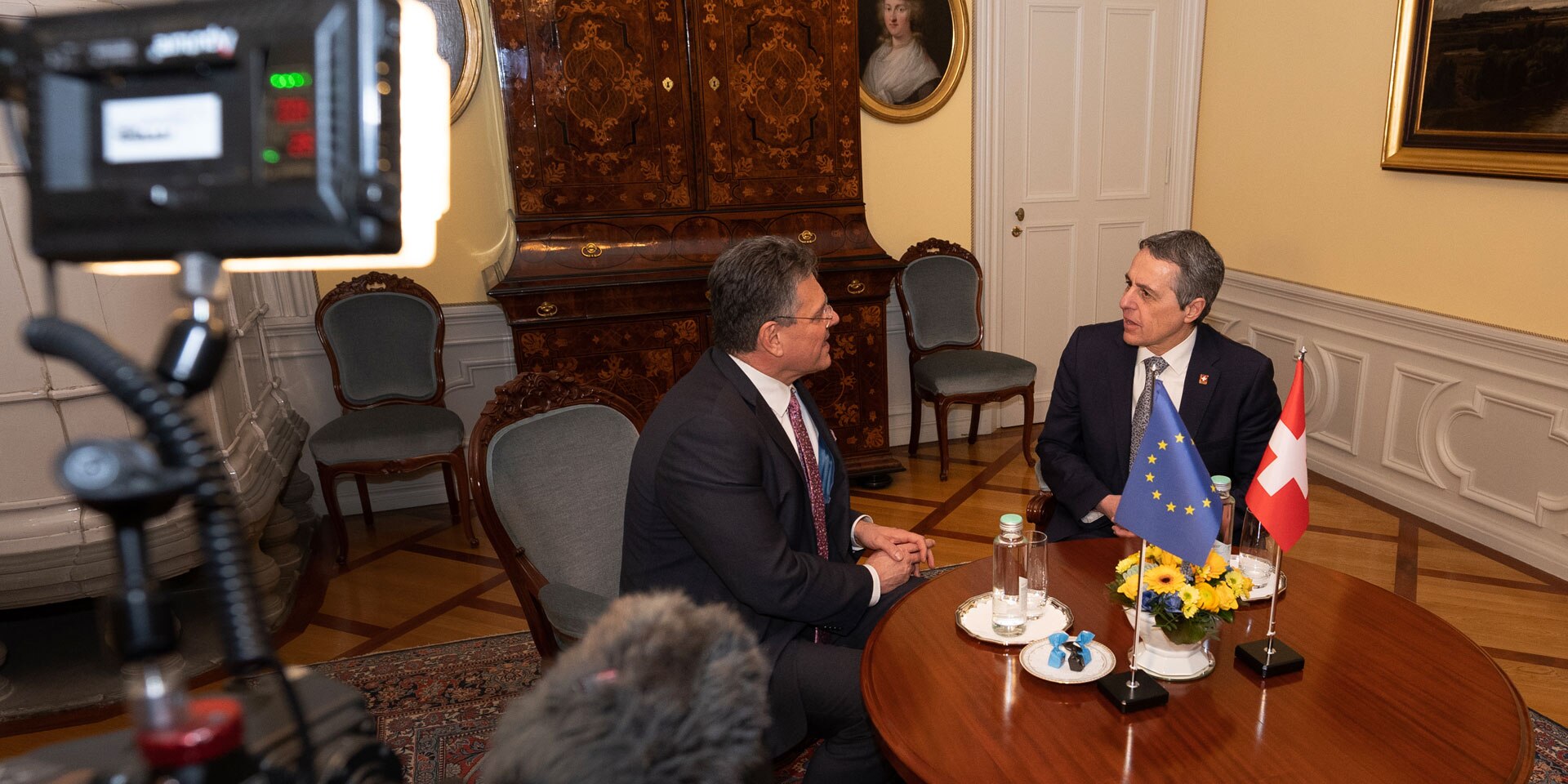 Ignazio Cassis et Maroš Šefčovič sont assis à une table. Les drapeaux suisse et européens y sont disposés.