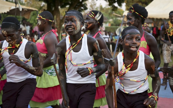 African children with painted faces dance.