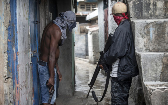 Zwei Gangmitglieder stehen mit einem Revolver und einem Gewehr bewaffnet in einer engen Gasse in Port-au-Prince, der Hauptstadt Haitis.