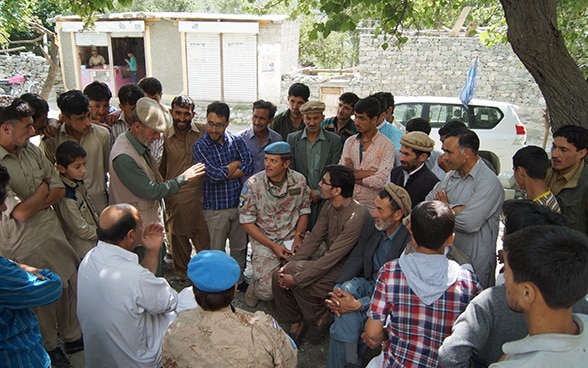 Ein Schweizer Militärbeobachter sitzt in einem Dorf in der Kaschmir-Region in der Mitte einer Personenmenge und hört deren Ausführungen an.
