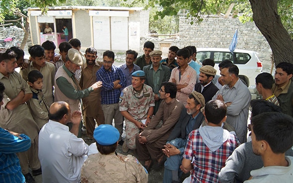 A Swiss military observer sits in the middle of a crowd of people in a village in the Kashmir region and listens to what they have to say.