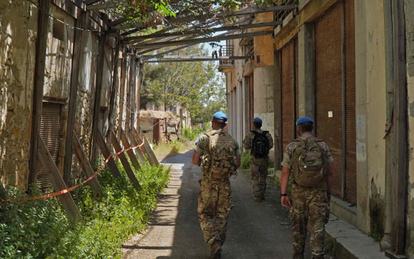 Membri della forza di mantenimento della pace delle Nazioni Unite (UNFICYP) camminano in un vicolo tra edifici fatiscenti nella zona cuscinetto.