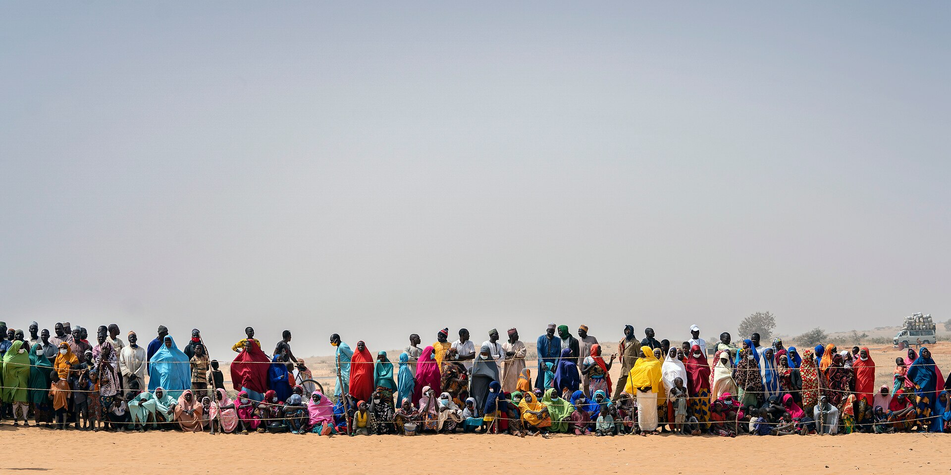 A group of people stand in a line behind a fence.