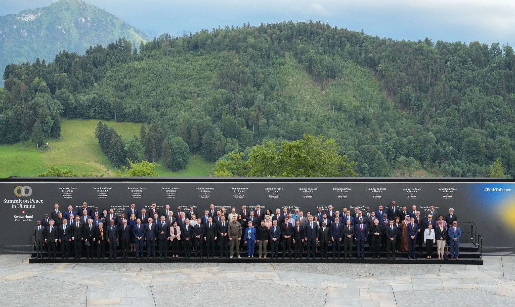 Vertreterinnen und Vertreter der 100 Delegationen posieren vor einer Wand mit dem Logo der hochrangigen Konferenz zum Frieden in der Ukraine.