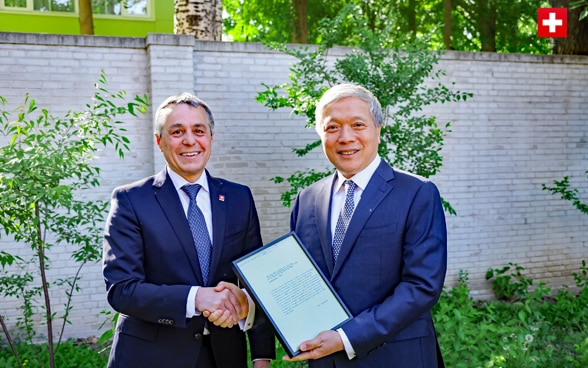 Bundesrat Ignazio Cassis und Botschafter Zhu Liying schütteln sich die Hände. 