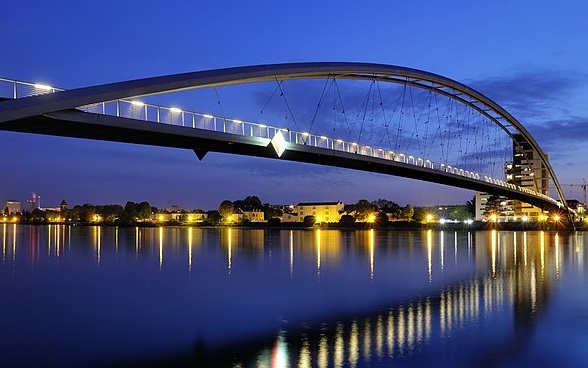Un ponte illuminato nella zona di confine tra Svizzera, Germania e Francia, in un’atmosfera serale.