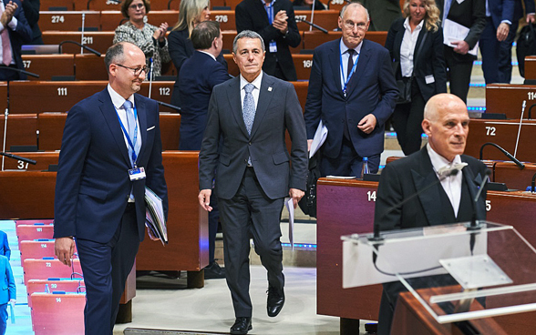 Men and women are walking into the hall of the Parliamentary Assembly. 