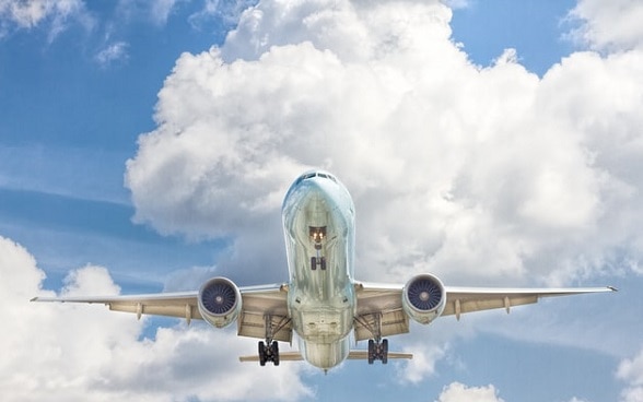 Un aereo in volo con le nuvole sullo sfondo.