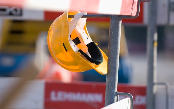 Ein Bauhelm ruht auf einer Bauabsperrung.