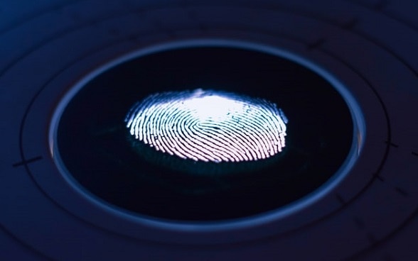  Illuminated fingerprint on a dark-coloured glass plate. 