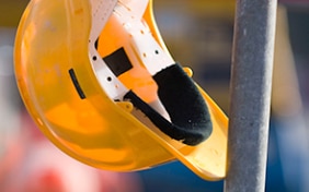 A yellow protection helmet hanging from scaffolding on a building site 