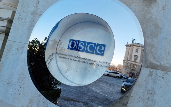 Le logo de l'OSCE sur le mur d'une maison derrière une vitre.