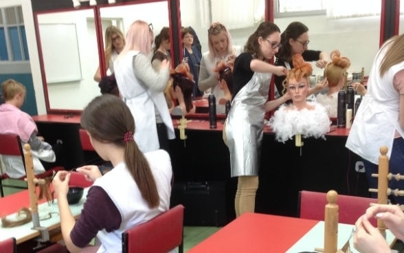 Junge Frauen üben an Puppen in einem Coiffeursalon.