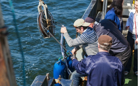 Researchers lower a side-scan sonar into the sea.