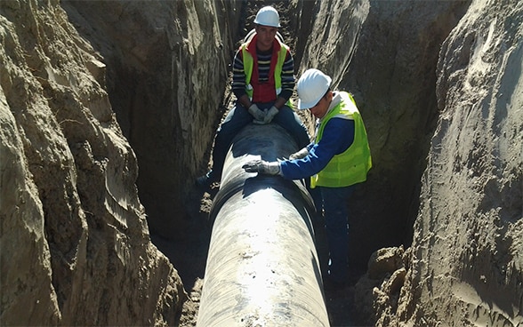 Two men working on a pipe. 