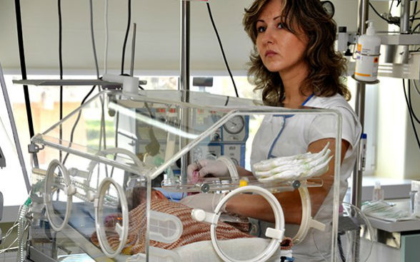 Dans un hôpital, une infirmière contrôle une couveuse pour bébés prématurés.