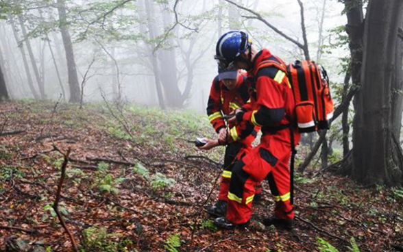 Au milieu d’une forêt, deux agents de la protection civile contrôlent leurs équipements.