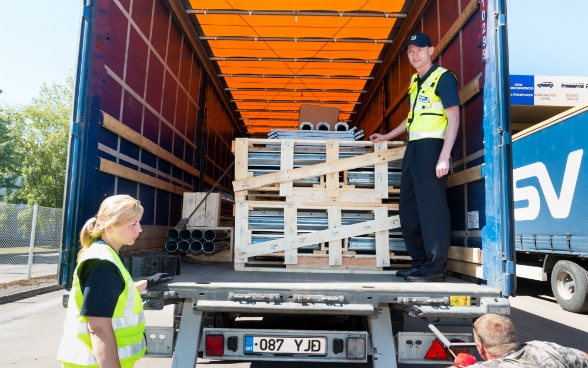 Deux fonctionnaires examinent le chargement d’un camion.