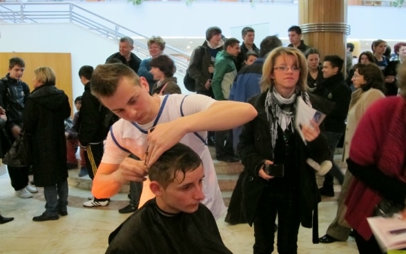 A un evento informativo sull’orientamento professionale, un giovane presenta il mestiere del parrucchiere.